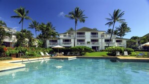 Un hotel con piscina, palmeras y un césped cuidado.