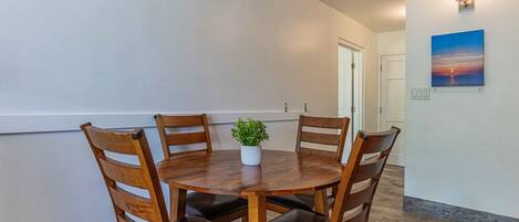 A dining area with a round wooden table, four chairs, and a small potted plant.