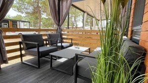 An outdoor patio area with a wooden deck, a sofa, and a table. - D&I Mobile Home (Privlaka)