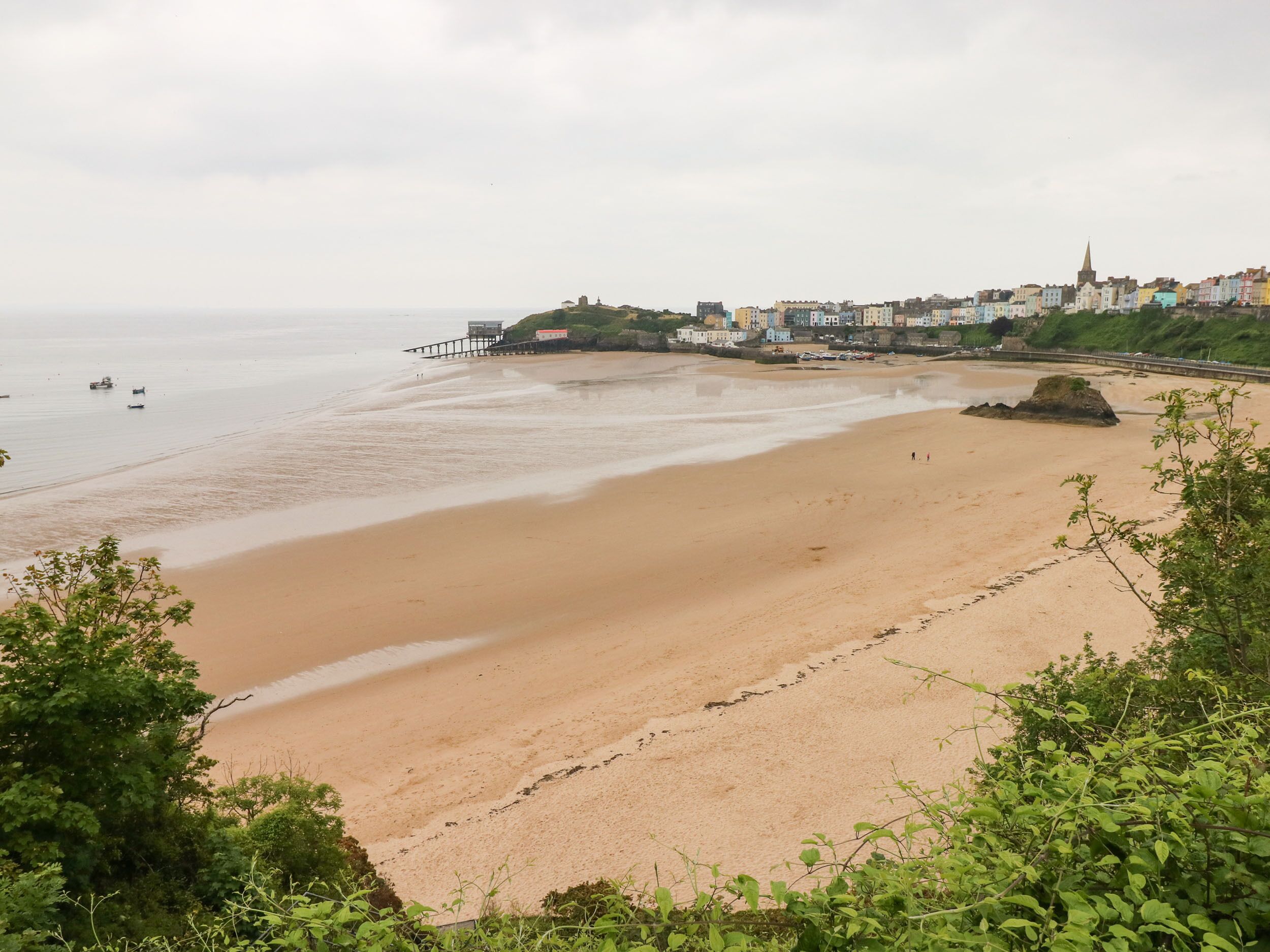 A beach with a pier, a church, and a town in the background.