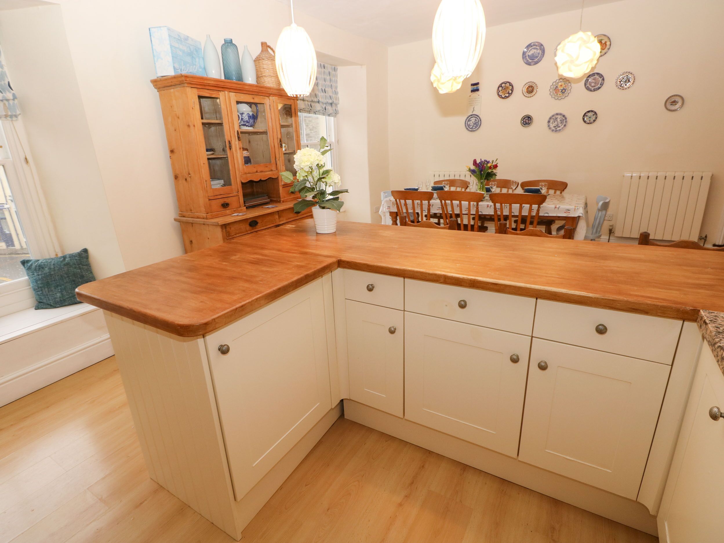 A kitchen with wooden cabinets, a wooden countertop, and a dining area with a table and chairs.