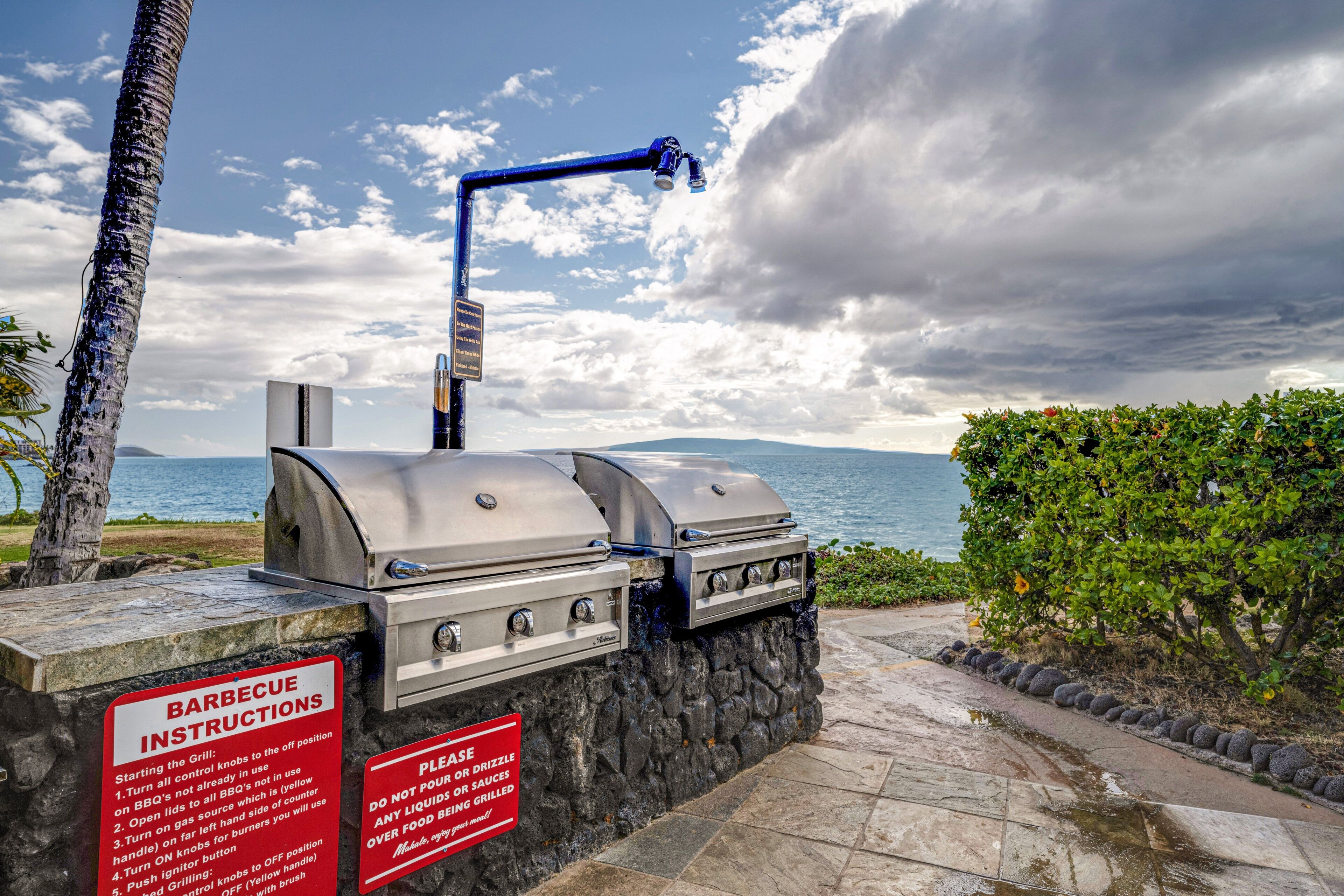 A barbecue grill with instructions, set against a scenic view of the ocean and a cloudy sky.