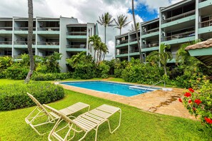 A hotel with a swimming pool, lounge chairs, and lush greenery.