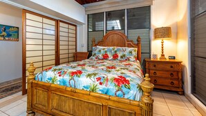 Un dormitorio con cama de madera, mesita de noche, lámpara y vistas al exterior.
