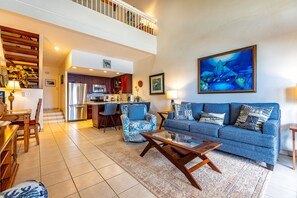 A spacious living area with a blue sofa, a coffee table, and a kitchen in the background.