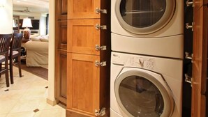 A laundry room with stacked washing machines and wooden cabinets.