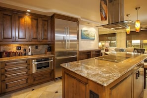 A modern kitchen with wooden cabinets, stainless steel appliances, and a marble countertop. - Kihei Beach, #102 2 Bedroom Condo by RedAwning (Kihei)