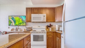 Una cocina con armarios de madera, un microondas, una estufa y un refrigerador.