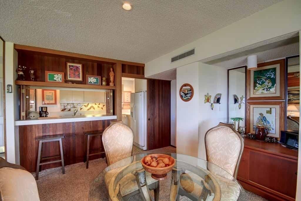 Un espacio habitable compacto con cocina, una mesa de comedor con sillas y una pequeña zona de bar.