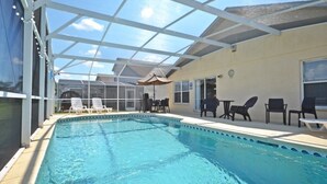 A swimming pool with lounge chairs and tables, surrounded by a covered patio area. - Bloomingdale Villa 4 Bedroom Home by RedAwning (Davenport)