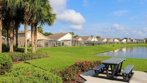 A residential area with a row of houses, a small pond, and a picnic table. - Bloomingdale Villa 4 Bedroom Home by RedAwning (Davenport)