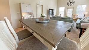 Un salon spacieux avec une table à manger en bois, un canapé et un téléviseur.