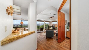 Une cuisine moderne dotée de plans de travail en granit, un coin repas avec une table et des chaises en bois, et une grande fenêtre offrant une vue sur l’extérieur.
