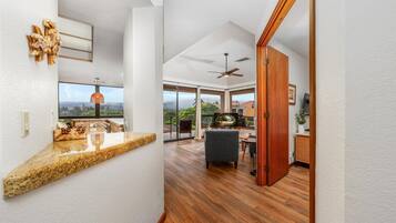 A modern kitchen with granite countertops, a dining area with a wooden table and chairs, and a large window offering a view of the outdoors.