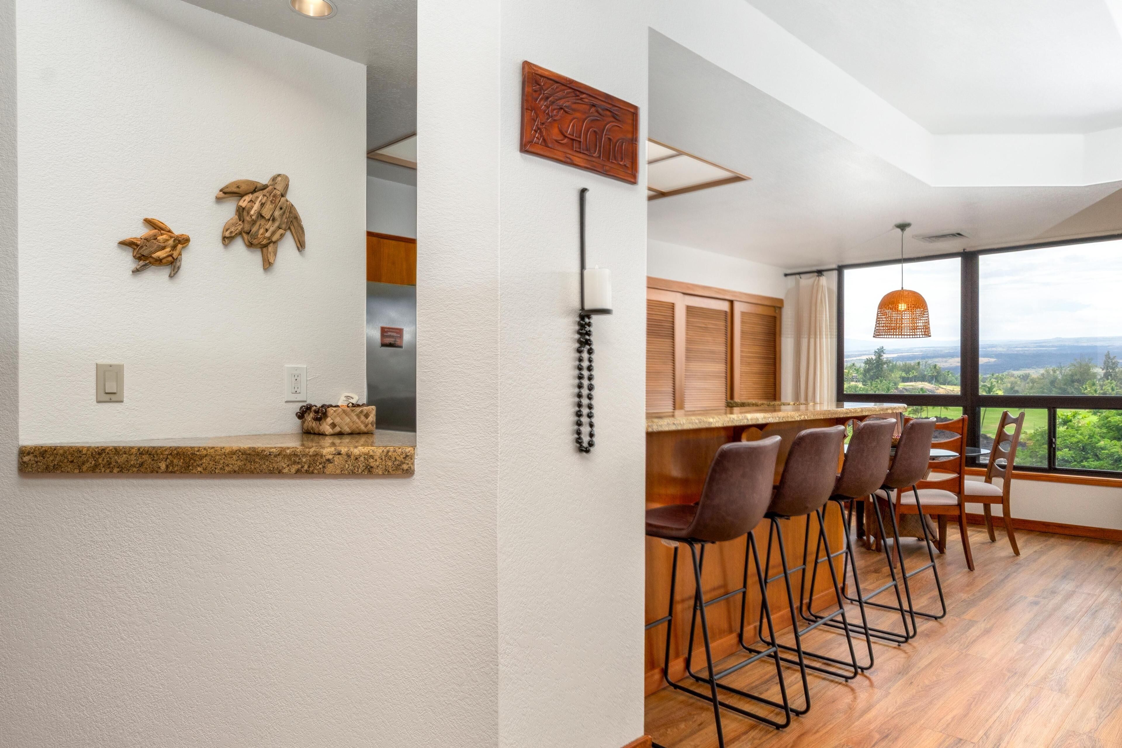 A modern kitchen with a bar area, wooden flooring, and a view of the outdoors.