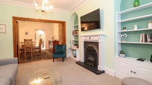 Una sala de estar con chimenea, televisión y estanterías.