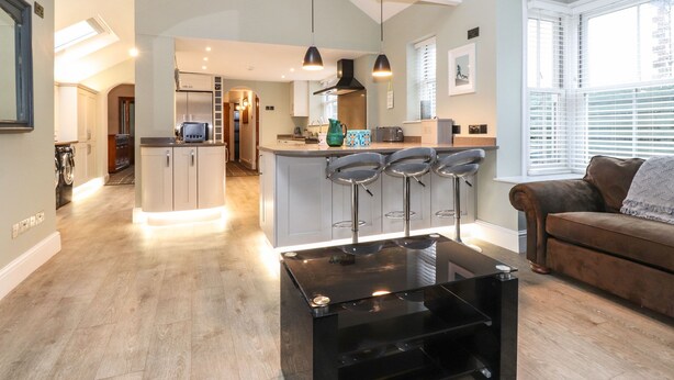 Una cocina moderna con una isla central, taburetes de bar e iluminación colgante.