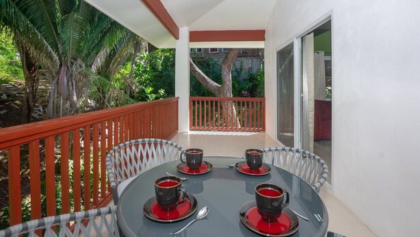 Ein Balkon mit einem Tisch für zwei Personen, zwei Tassen Kaffee und einem rot-weiß gestreiften Stuhl.