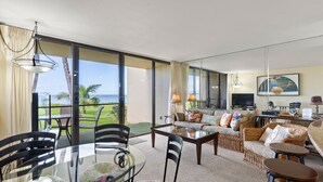 A spacious living area with a glass table, chairs, a sofa, and a television. - Sugar Beach Resort, #130 1 Bedroom Condo by RedAwning (Kihei)