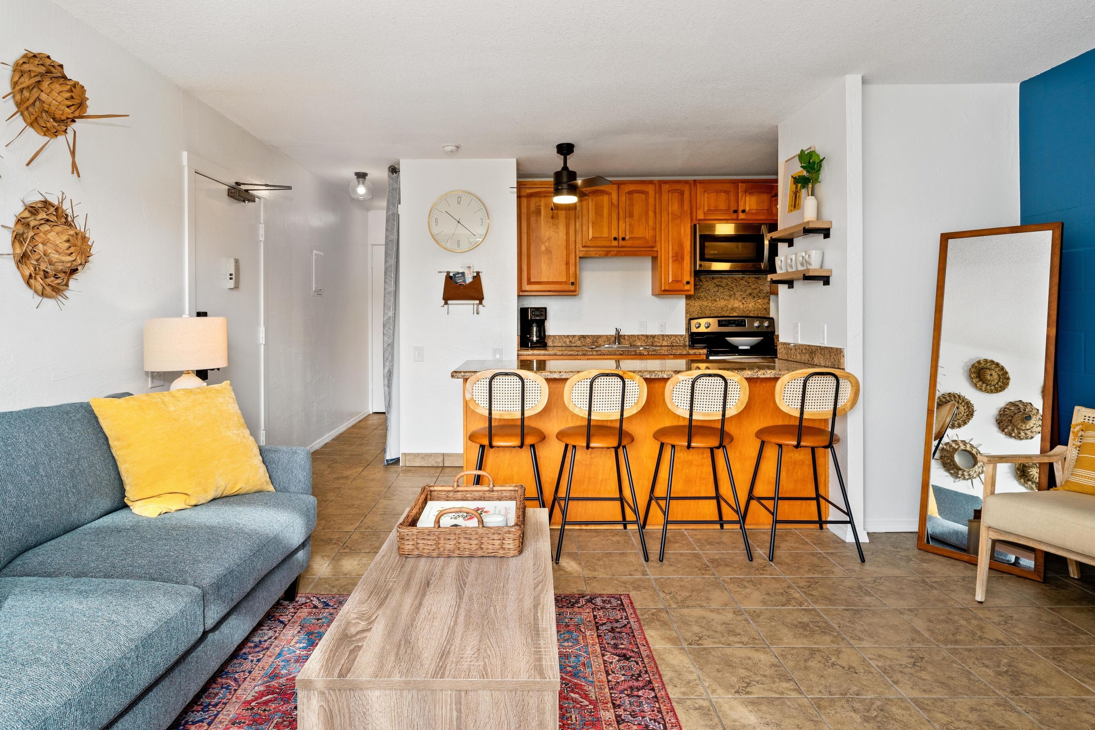 A modern living room with a sofa, coffee table, and a kitchen area with bar stools.