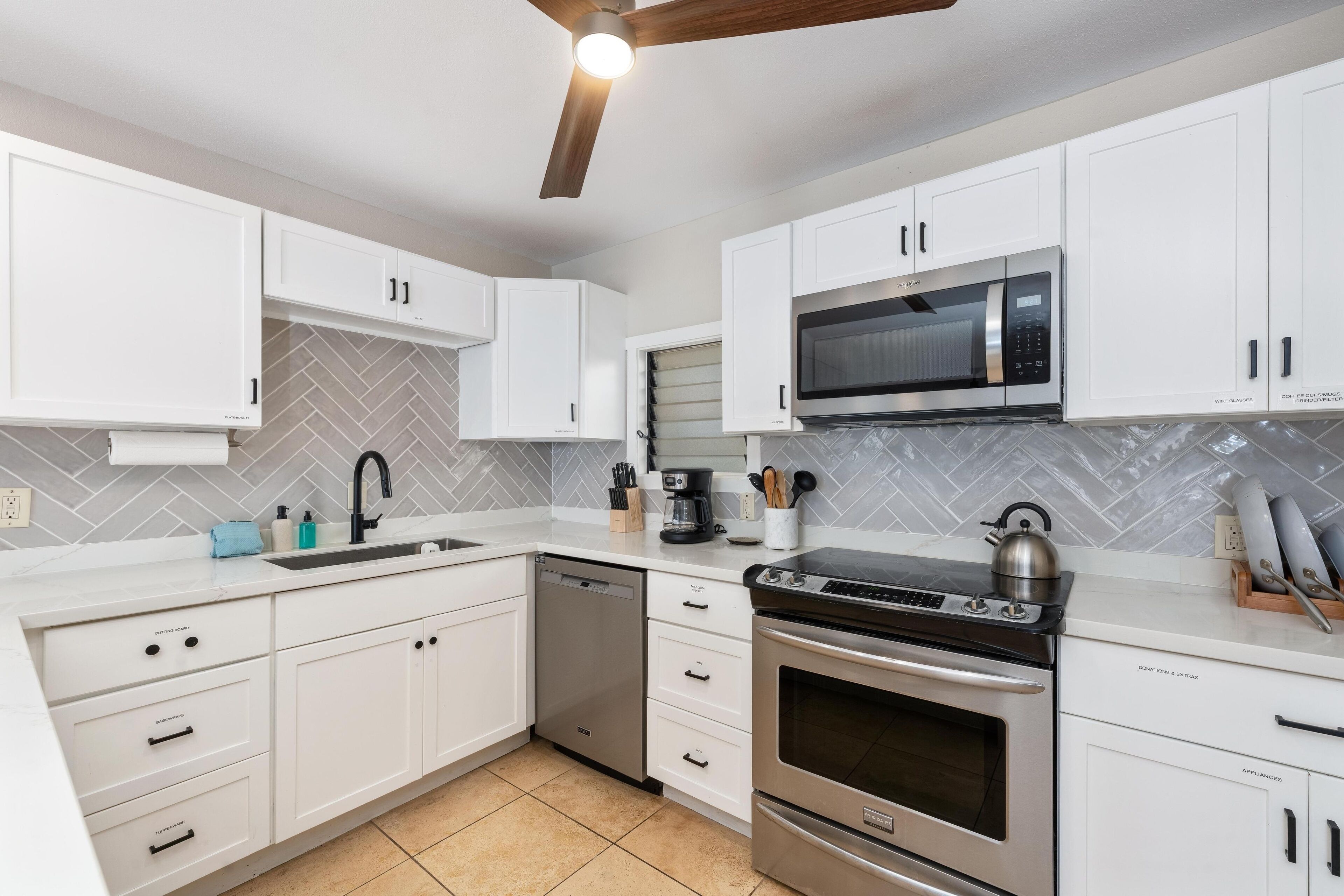 A modern kitchen with white cabinetry, a built-in microwave, a stove, and a dishwasher.