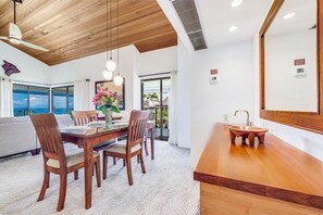 A dining area with a wooden table and chairs, a large window with a view, and a wooden ceiling. - Wailea Elua, #0302 1 Bedroom Condo by RedAwning (Kihei)