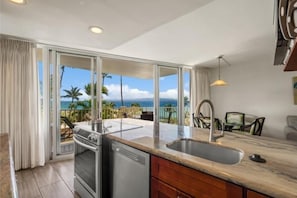 A kitchen with a view of the ocean, a dishwasher, and a sink.