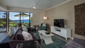 Un soggiorno moderno con divano, tavolino, televisore e un balcone con vista sull'oceano.