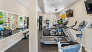 Una palestra con attrezzature per esercizi, uno specchio e un televisore appeso al muro.