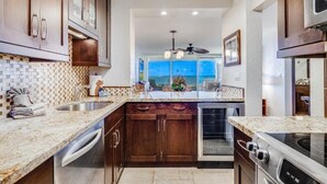 A kitchen with wooden cabinets, a built-in oven, and a view through the window. - Menehune Shores, #115^ 3 Bedroom Condo by RedAwning (Kihei)