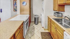 A compact kitchen with a stove, sink, and a toaster.