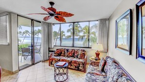 A room with a sofa, a small round table, and a ceiling fan.