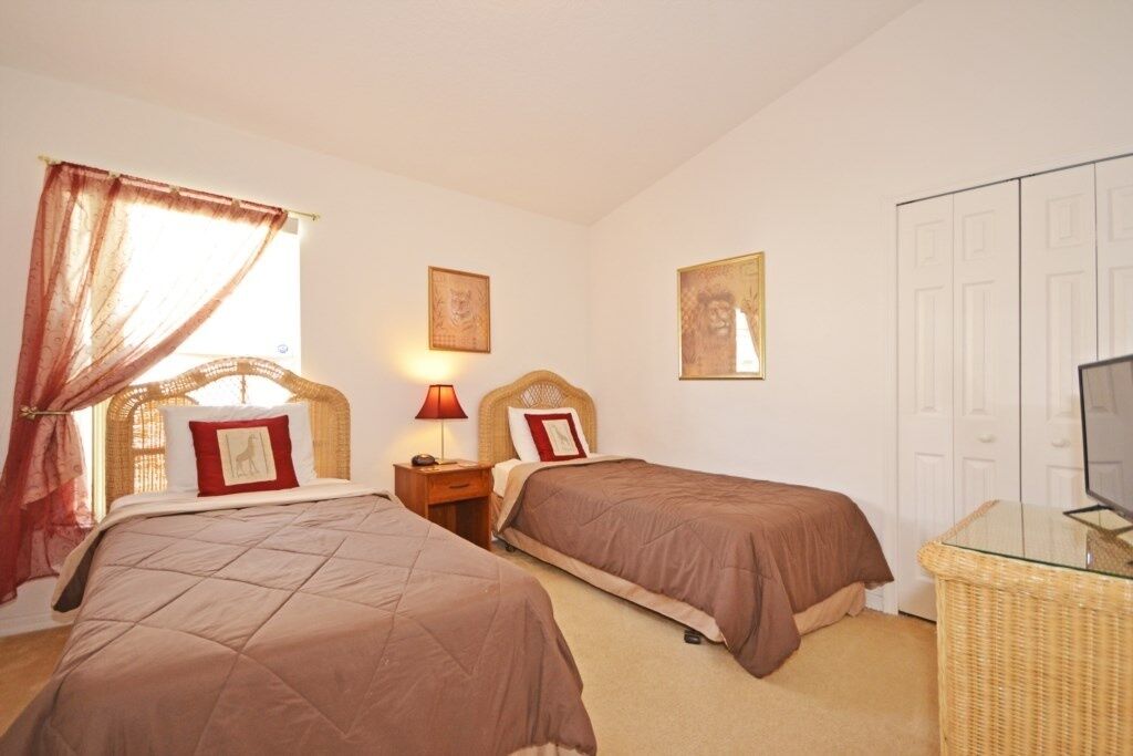 A hotel room with two beds, a television, and a wicker chair.