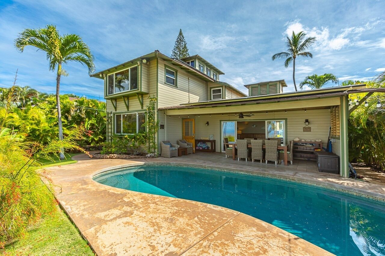 Une maison à deux étages dotée d’une piscine, d’un espace extérieur aménagé et d’une végétation tropicale.
