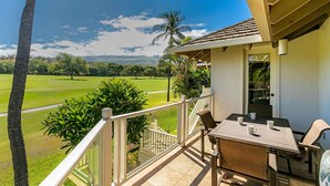 A balcony with a table and chairs, overlooking a golf course.