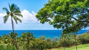 A golf course with palm trees and a view of the ocean. - Big Island Keauhou Akahi #311 1 Bedroom Home (Kailua-Kona)