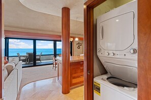 Un cuarto de lavandería con vista al océano, un gabinete de madera y un espacio de descanso con una mesa y sillas.