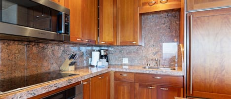 A kitchen with wooden cabinets, granite countertops, stainless steel appliances, and a built-in oven.