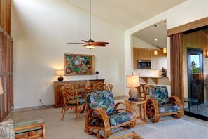 A room with wicker furniture, a ceiling fan, a dining table with chairs, and a kitchen area visible through an open doorway. - Wailea Ekahi, #22d 1 Bedroom Condo by RedAwning (Kihei)
