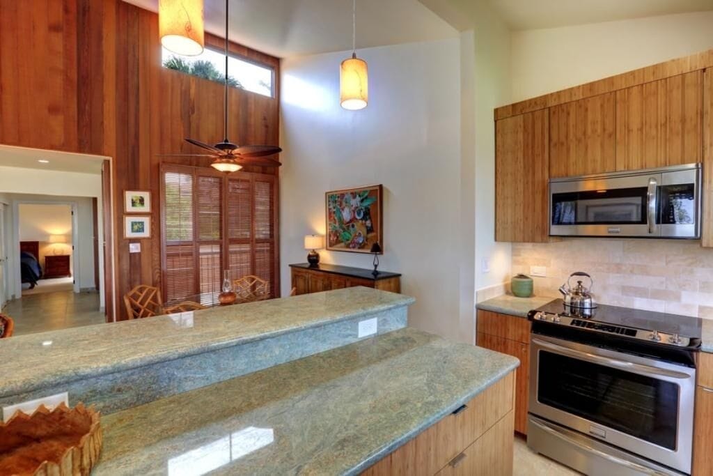 A kitchen with wooden cabinets, a microwave, an oven, and a granite countertop.
