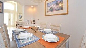 Een eetkamer met een houten tafel voor vier personen, witte borden en blauwe placemats.