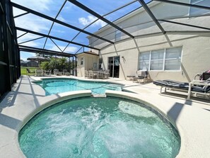 Un espace extérieur abrité avec une piscine, des chaises longues et un bâtiment en arrière-plan.