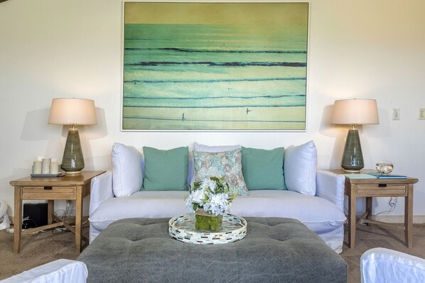 A bedroom with a bed, two nightstands, a large abstract painting, and a decorative plant centerpiece. - Wailea Ekolu Two Bedrooms by Coldwell Banker Island Vacations (Kihei)