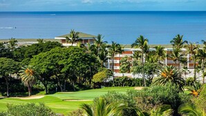 A golf course with a view of the ocean and a hotel in the background.