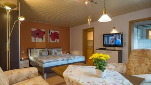 Une chambre d’hôtel avec un lit, une télévision, une table ornée d’un vase de fleurs et un canapé.