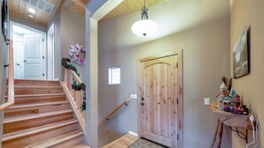 Una escalera de madera que lleva a una habitación con una puerta de madera, una ventana pequeña y un estante con un tren de juguete.