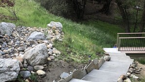 Un sendero de hormigón bordeado de rocas que conduce a una terraza de madera.