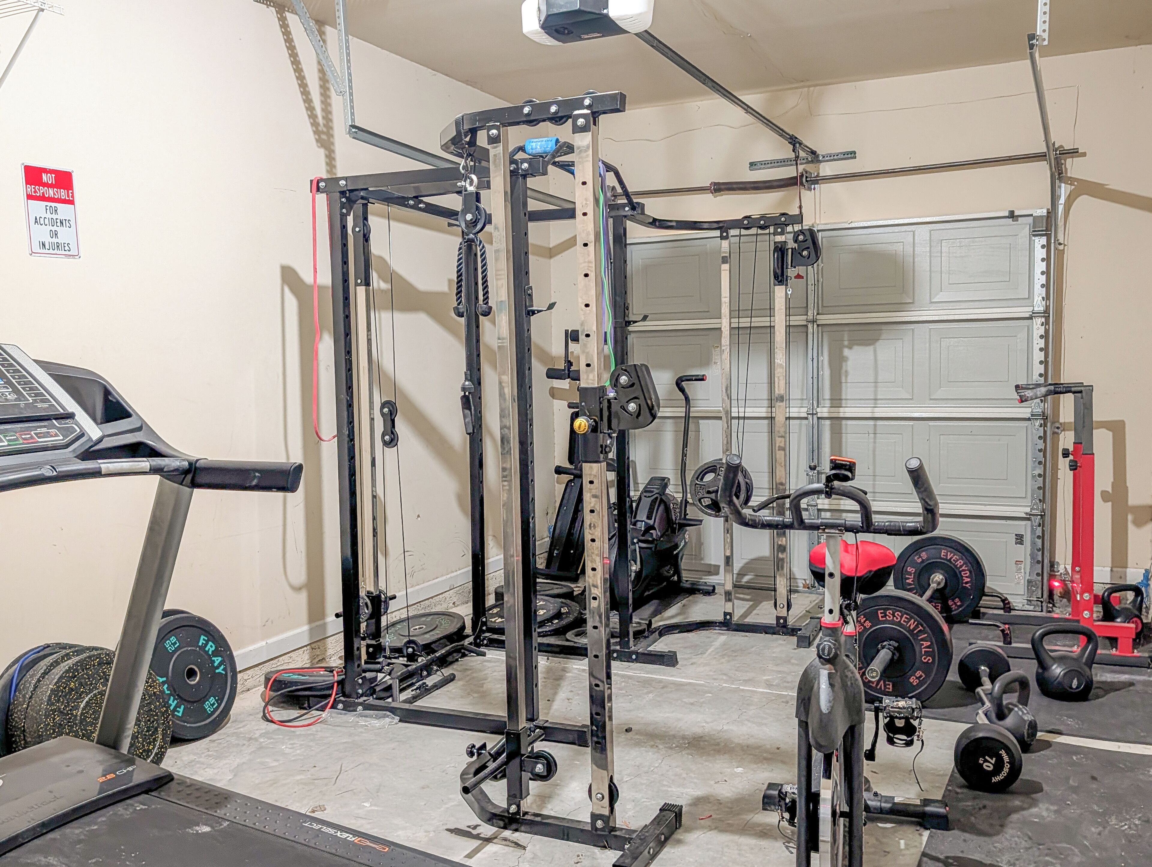 A home gym with a squat rack, weight plates, a bench press, and a treadmill.
