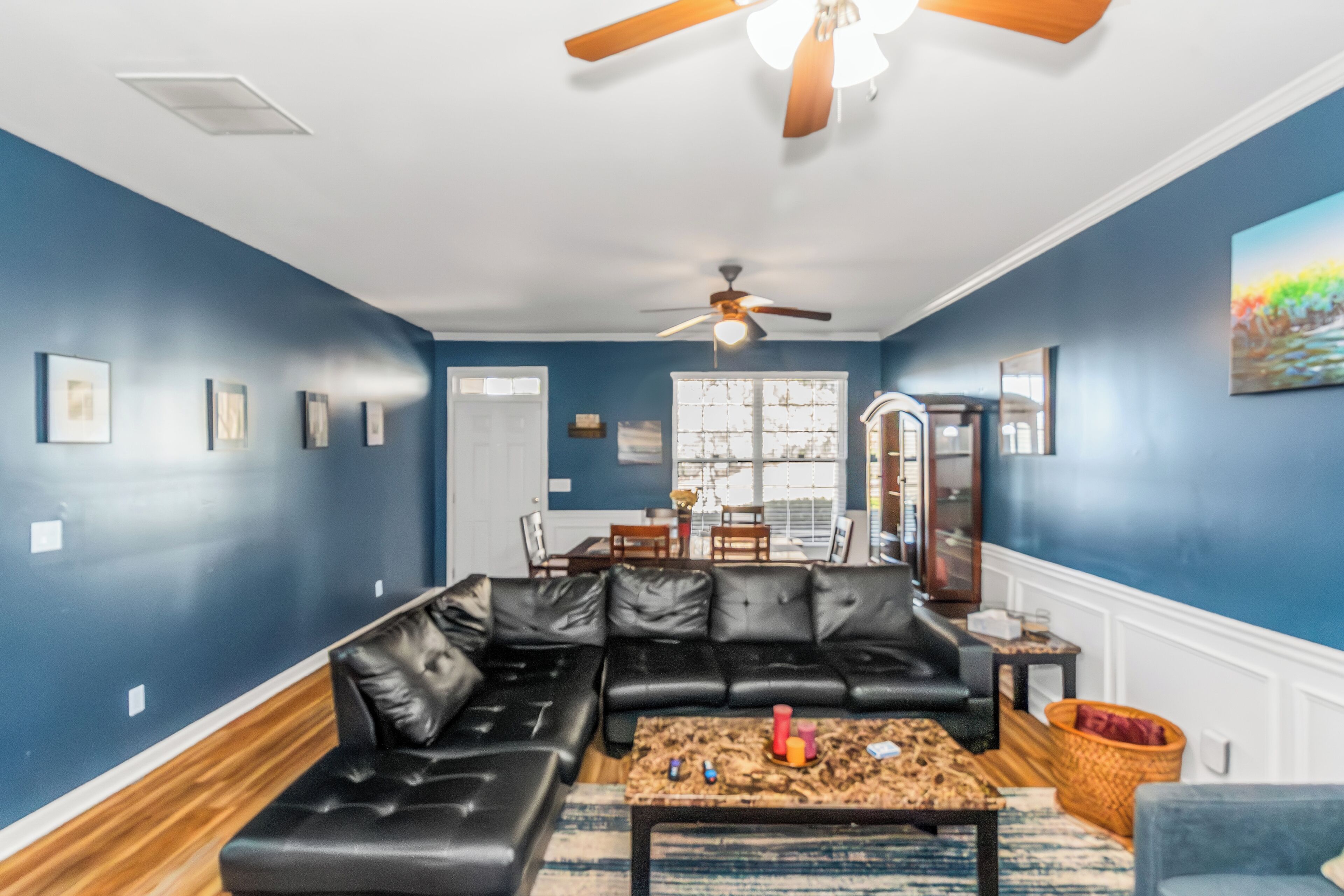 A living room with a sectional sofa, a coffee table, and a ceiling fan.
