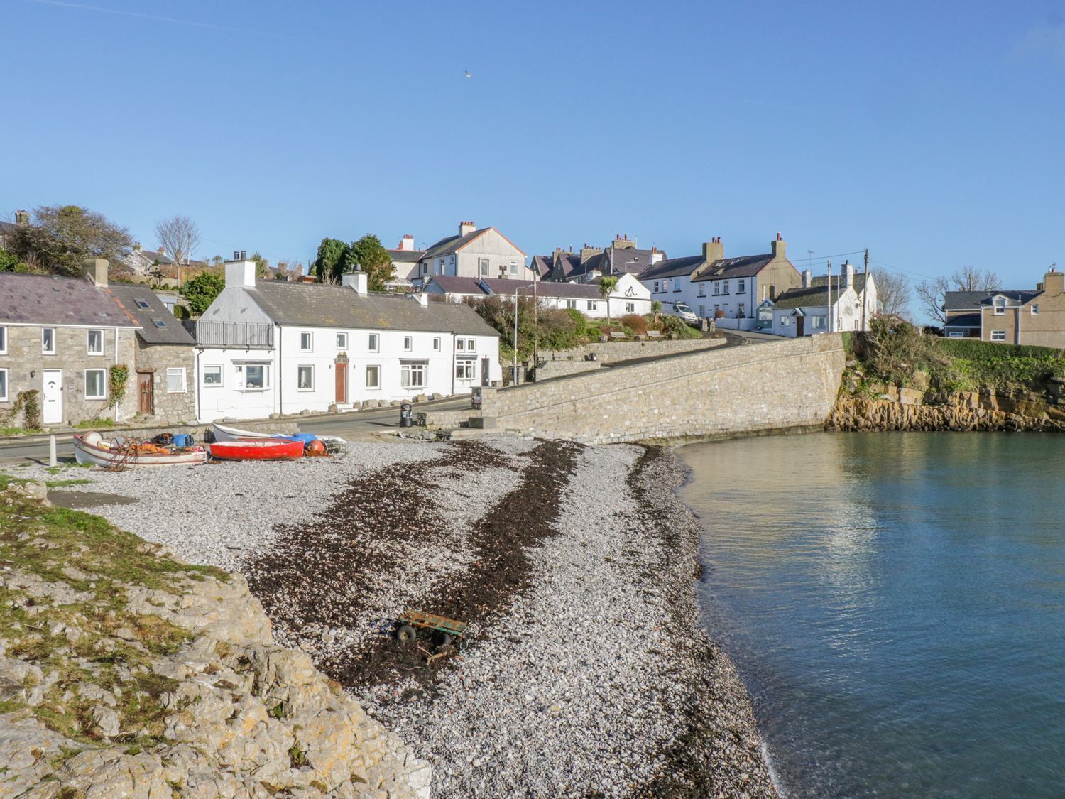A coastal town with stone buildings, a small harbor, and a clear sky.
